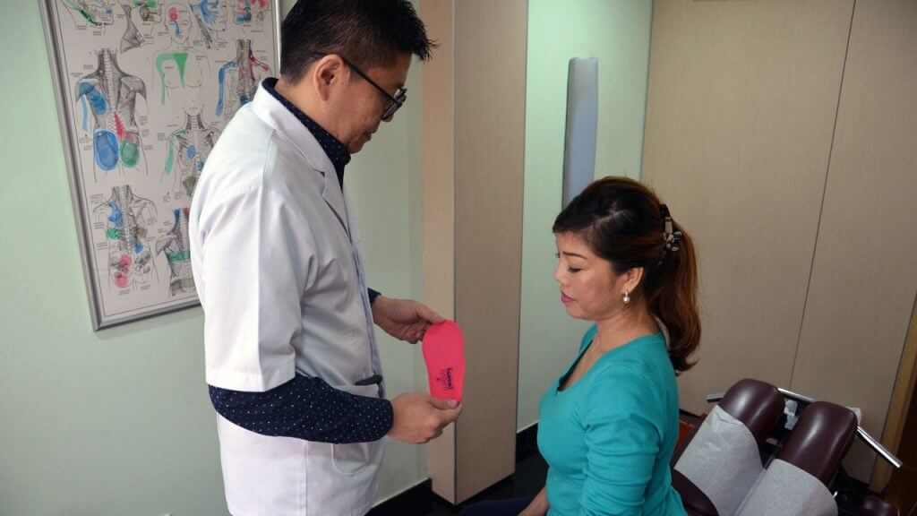 Chiropractor showing patient adult orthotics for foot pain