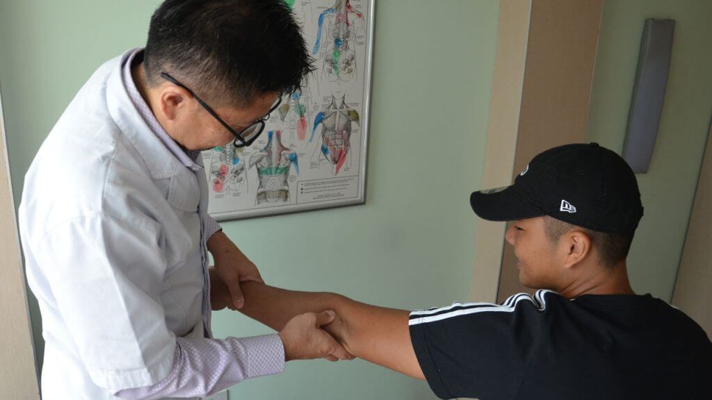 Chiropractor providing patient elbow pain treatment