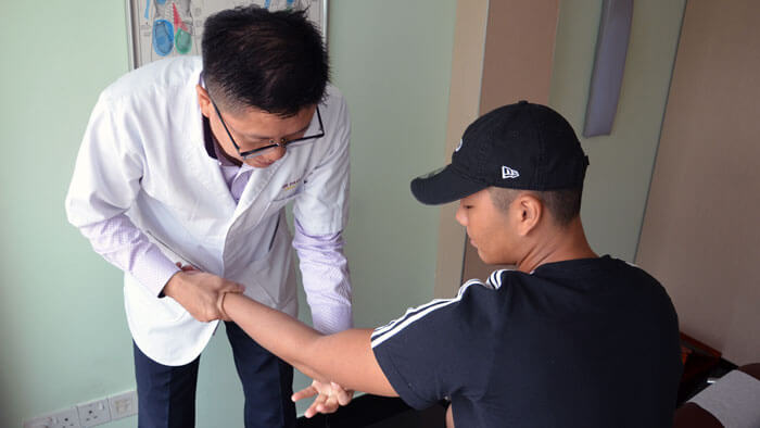Chiropractor providing patient golfer's or tennis elbow pain treatment